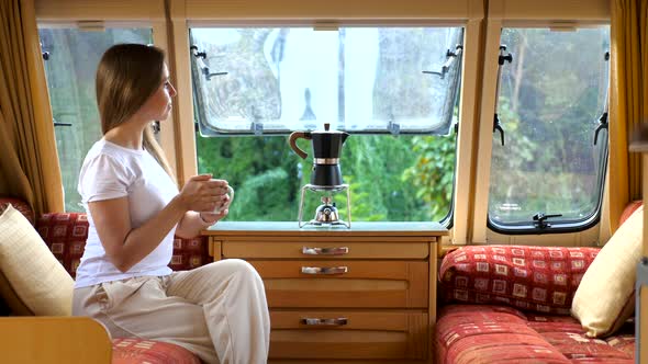 Woman in Interior of Camper RV Motorhome with Cup of Coffee Looking at Nature