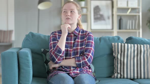 Young Woman Sitting on Couch And Thinking