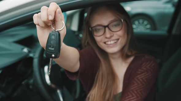 Young Caucasian Happy Woman Sitting on the Driver Seat in the Car and Holding Keys