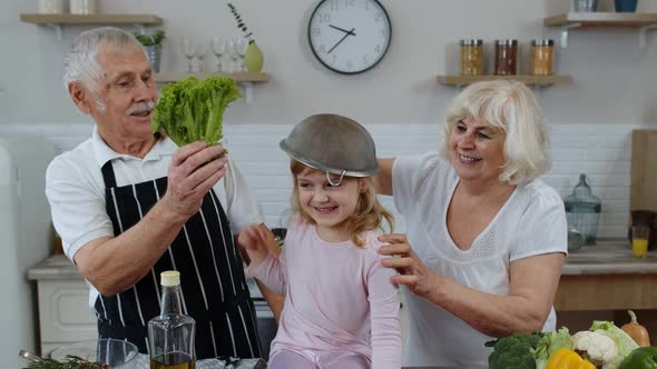 Senior Woman and Man with Grandchild Girl Fooling Around with Strainer and Vegetables at Home