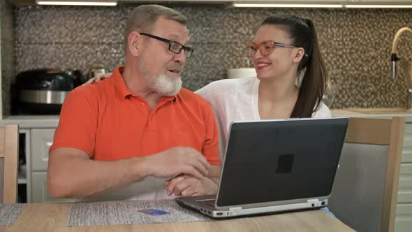 Beautiful Young Woman Is Explaining To Her Elderly Father How To Shop and Various Payments Online