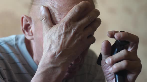 Close-up portrait of an elderly man in desperation holding his hand to his head and holding a walkin