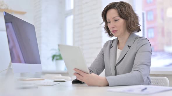 Creative Old Woman Using Tablet on Office Desk