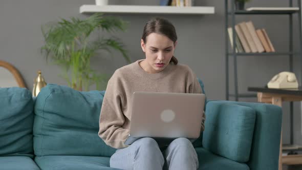 Woman with Laptop Feeling Worried on Sofa