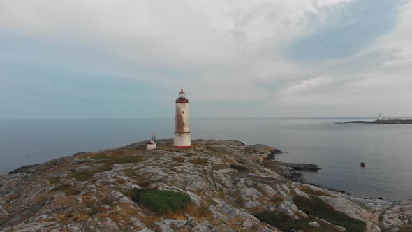 Aerial drone shot wide orbit around of Tiny Torungen Lighthouse in Norway where it stands on its roc