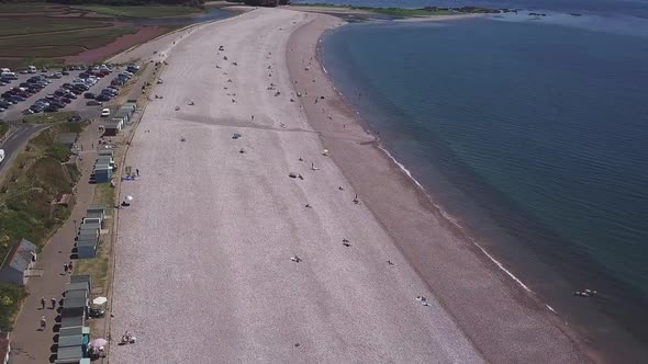 Flying over Budleigh beach in southwest England where people are enjoying a day outside sitting at t