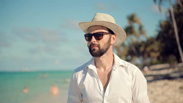 Man Walking On Tropical Beach. Guy Relaxing On Caribbean Beach. Tanned Man In Hat Healthy Skin.