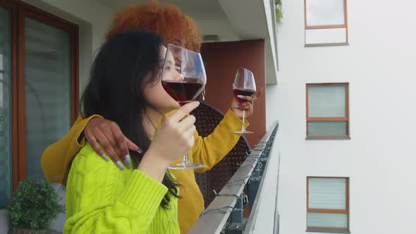 Couple of Young Interracial Women, Best Friends or Lesbian Couple, Drinking Wine on the Balcony