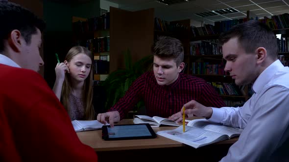 Group of Students Sitting at a Table in a Library, Camera Moves To the Right