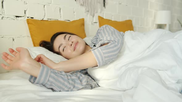 Slow Motion of Asian Woman Sleeping Then Waking Up Smiling and Stretching in Bed at Home