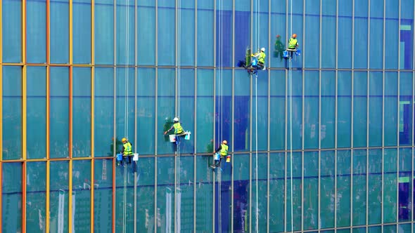 Five Workers in Protective Covid Masks and Blue and Yellow Work Clothes are Washing the Outside