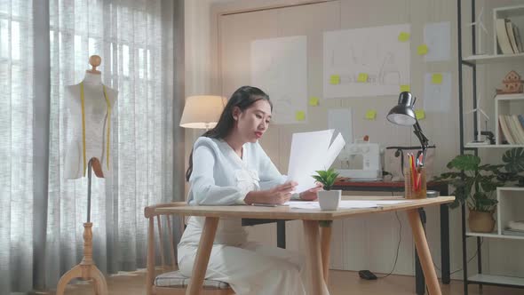 Asian Woman Designer Positively Shaking Her Head While Looking At The Layout Bond At The Office