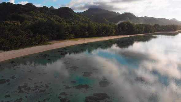 Aerail footage of white sand beach and reflections in the lagoon in the early morning in the Raroton