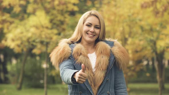 Happy Woman Smiling and Showing Thumbs Up in Autumn Park, Social Insurance