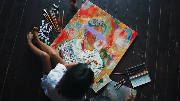 Woman Artist is Painting a Portrait on Canvas in Concept Art Style While Sitting on a Wooden Floor