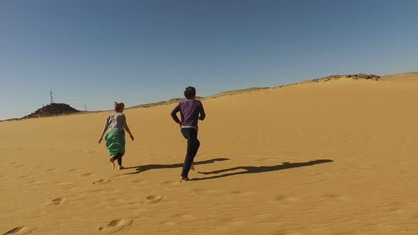 Couple running barefoot in desert, Egypt