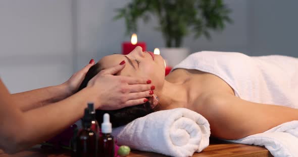 Therapist Massaging Head of Woman in Spa Center