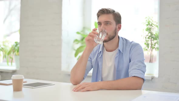 Young Creative Man Drinking Water in Modern Office