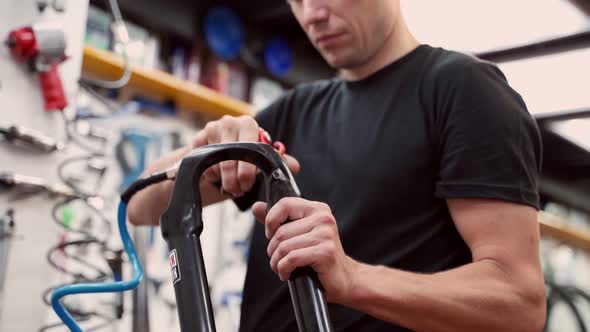 Anonymous mechanic cleaning bicycle fork with air blow gun