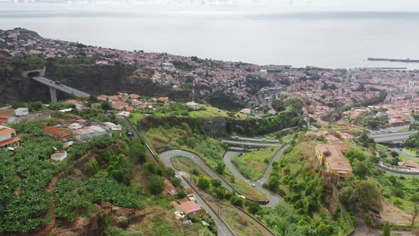 Aerial Footage of a Cable Car Moving Along Green Valley with Houses