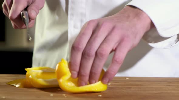 Cook cuts fresh ripe yellow peppers with sharp knife.