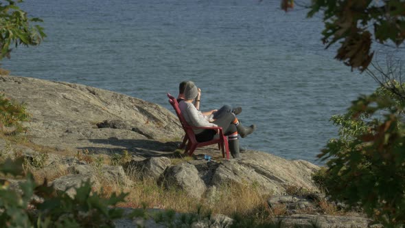 Tourists relaxing on the rocky shore of a lake