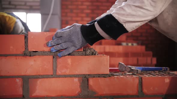 builder lays red brick close-up