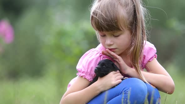 Pretty Child Girl Playing with Little Puppy Outdoors in Summer