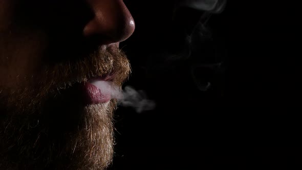 Man with a Beard Smoking Electronic Cigarette. Black. Close Up