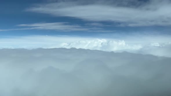 Overflying layers of clouds. Aerial view from a jet cockpit, during cruise level, daylight.