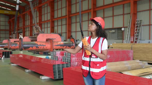 Young woman engineers testing and checking the operation of crane in the factory.