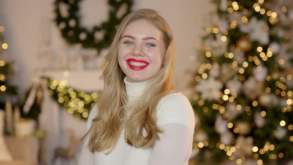 Fashionable Smiling Woman Wearing Knitwear Cozy Sweater in Front of Christmas Tree