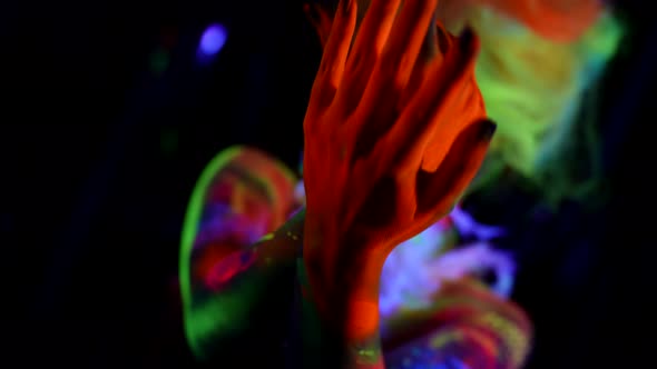 Mysterious Female Figure in Darkness Woman is Moving Hands Covered Fluorescent Paints