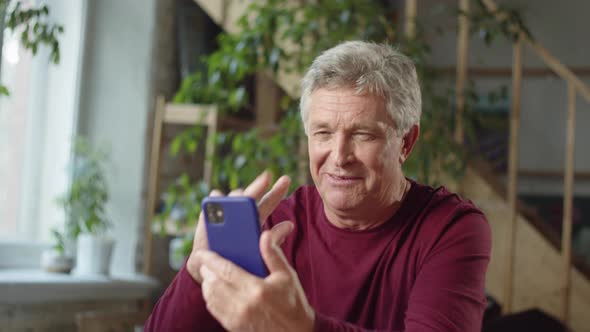 Pensioner Talking By Video Call on the Phone Waving His Hand and Smiling