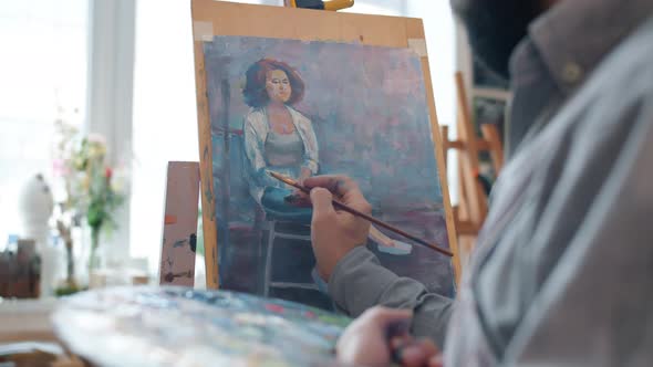 Talented Male Artist Creating Portrait of Young Woman Working Indoors in Workshop