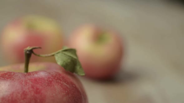 Red apple with stalk close up with out of focus hands stacking apples in background