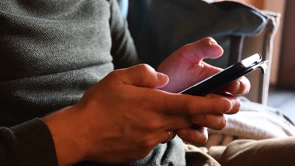 Male hands tapping and swiping his smartphone closeup