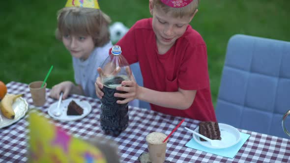 Cheerful Boy Spilling Soda Water Pouring Drink in Paper Cup in Slow Motion on Birthday Party