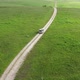 Aerial view on the driving car of the mountain road through the green field - VideoHive Item for Sale