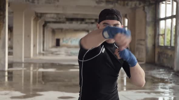 Young Boxer Practicing Boxing Punches Looking at Camera in Abandoned Building