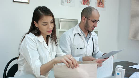 Two Busy Doctors Working with Papers and Xray Images, Answering Phone Calls, Prescribing Pills at