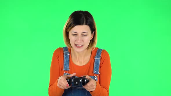 Girl Playing a Video Game Using a Wireless Controller with Joy and Loses. Green Screen