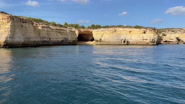 Short outcrop sea cliff large sea cave, view from boat sailing on ocean