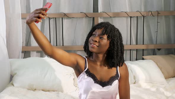 Lady Makes Selfie Fixing Curly Hair and Holding Smartphone