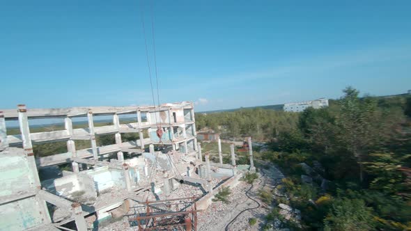 FPV Drone Flies Smoothly Among Abandoned Industrial Buildings and Around an Excavator