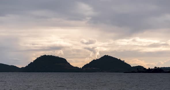 Timelapse of a sunset with clouds and two mountains at the mouth of the pacific ocean