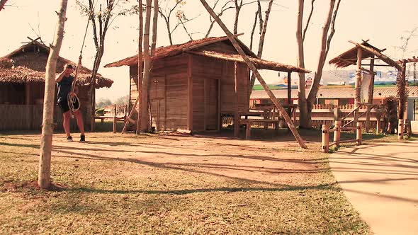 A tourist playing with a traditional swing in the village of the Lua Tribe in Chiang rai Thailand