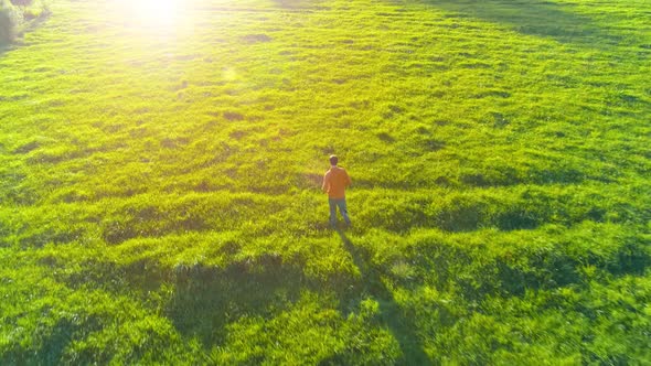 Flight Over Sporty Man Running at Perfect Green Grass Rural Meadow Offroad. Sunset in Mountain