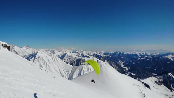 Paroplane Fly Above Snowy Mountains.