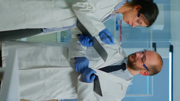 Vertical Video Scientists Coworkers Using Digital Tablet Working in Medical Research Laboratory